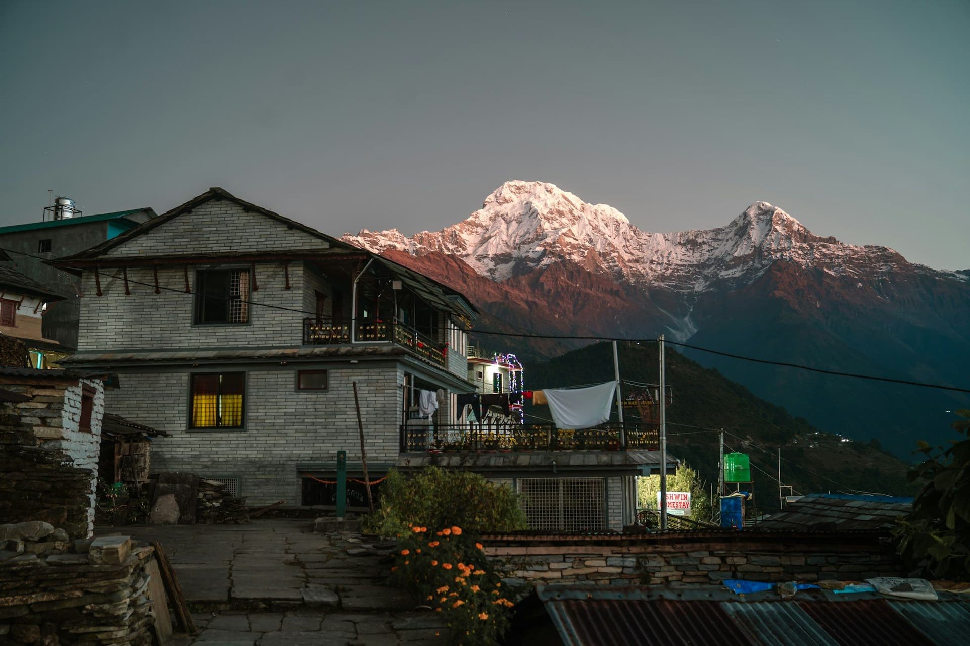 A village lodge at dawn with Annapurna South lit pink behind