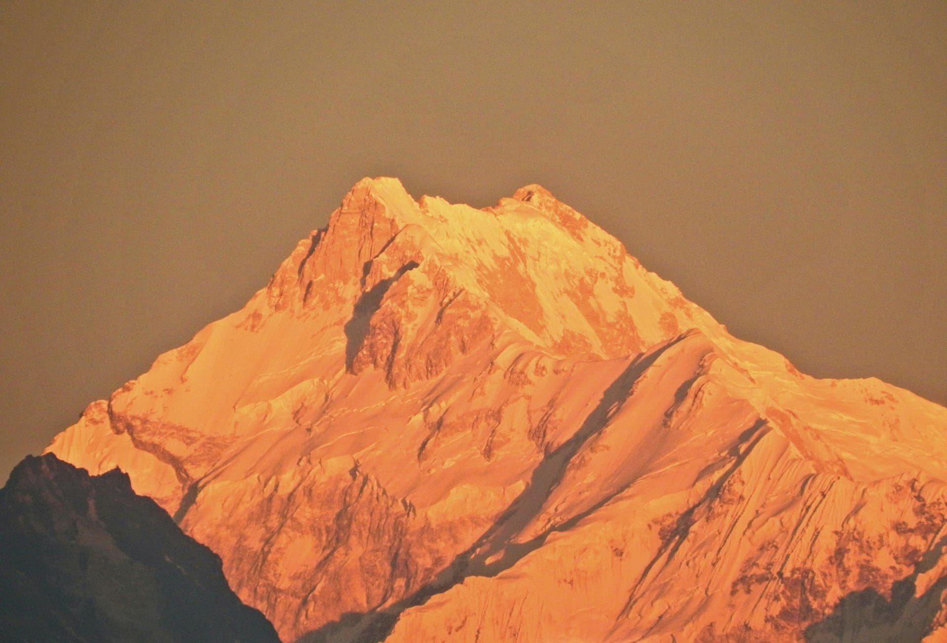Kanchenjunga's summit ridge lit orange at sunrise