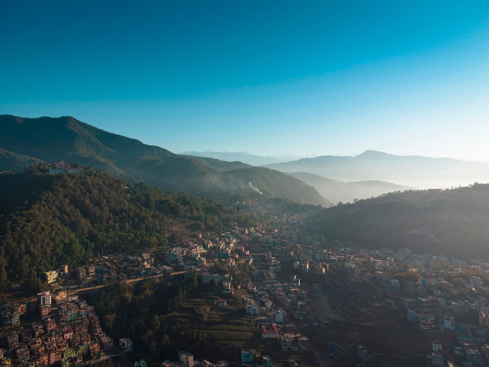 A hillside town with valley ridges receding into haze