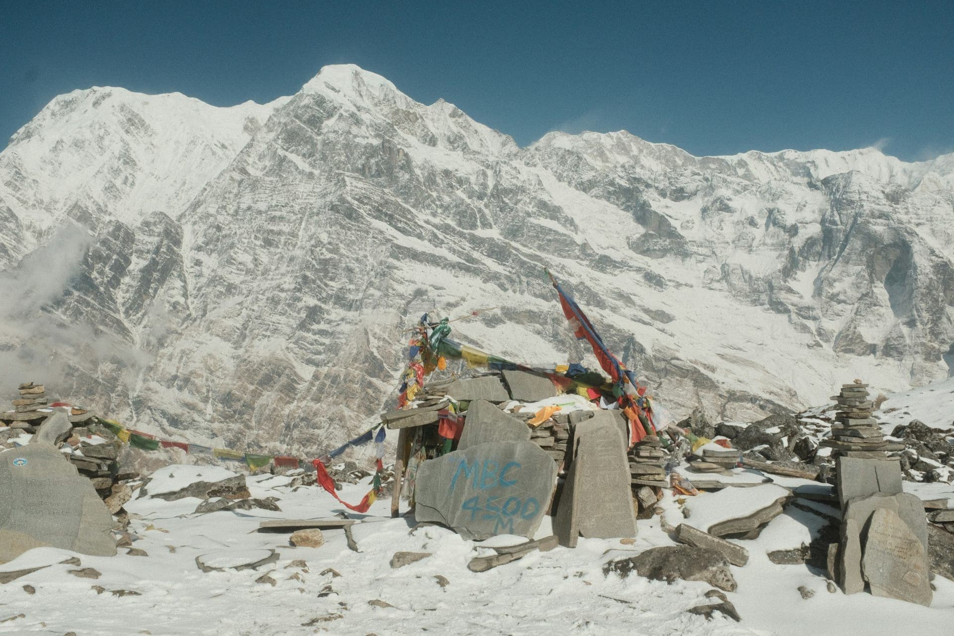 Prayer flags and stone cairns on a snowbound high point