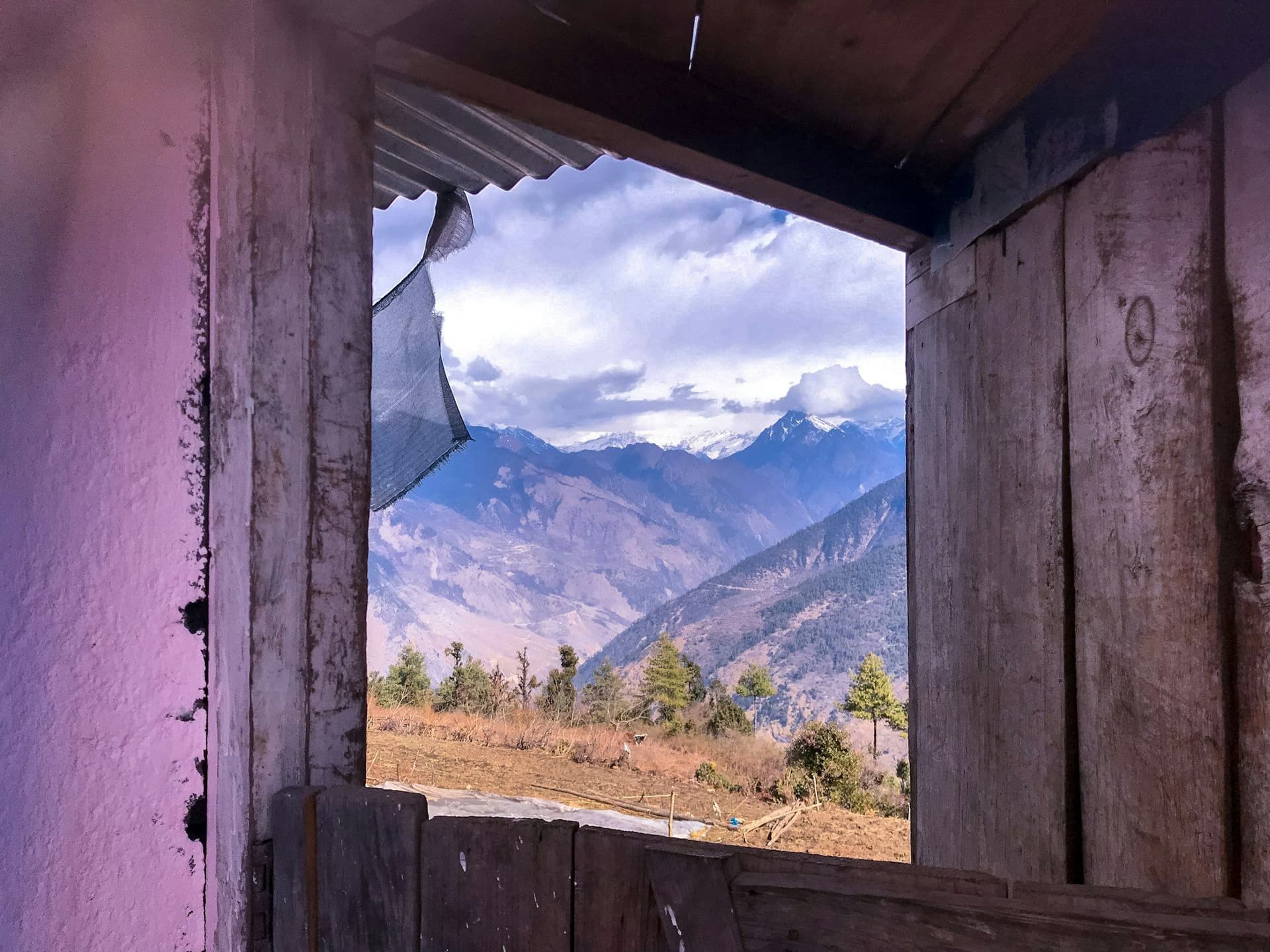 A mountain range seen through an open lodge window