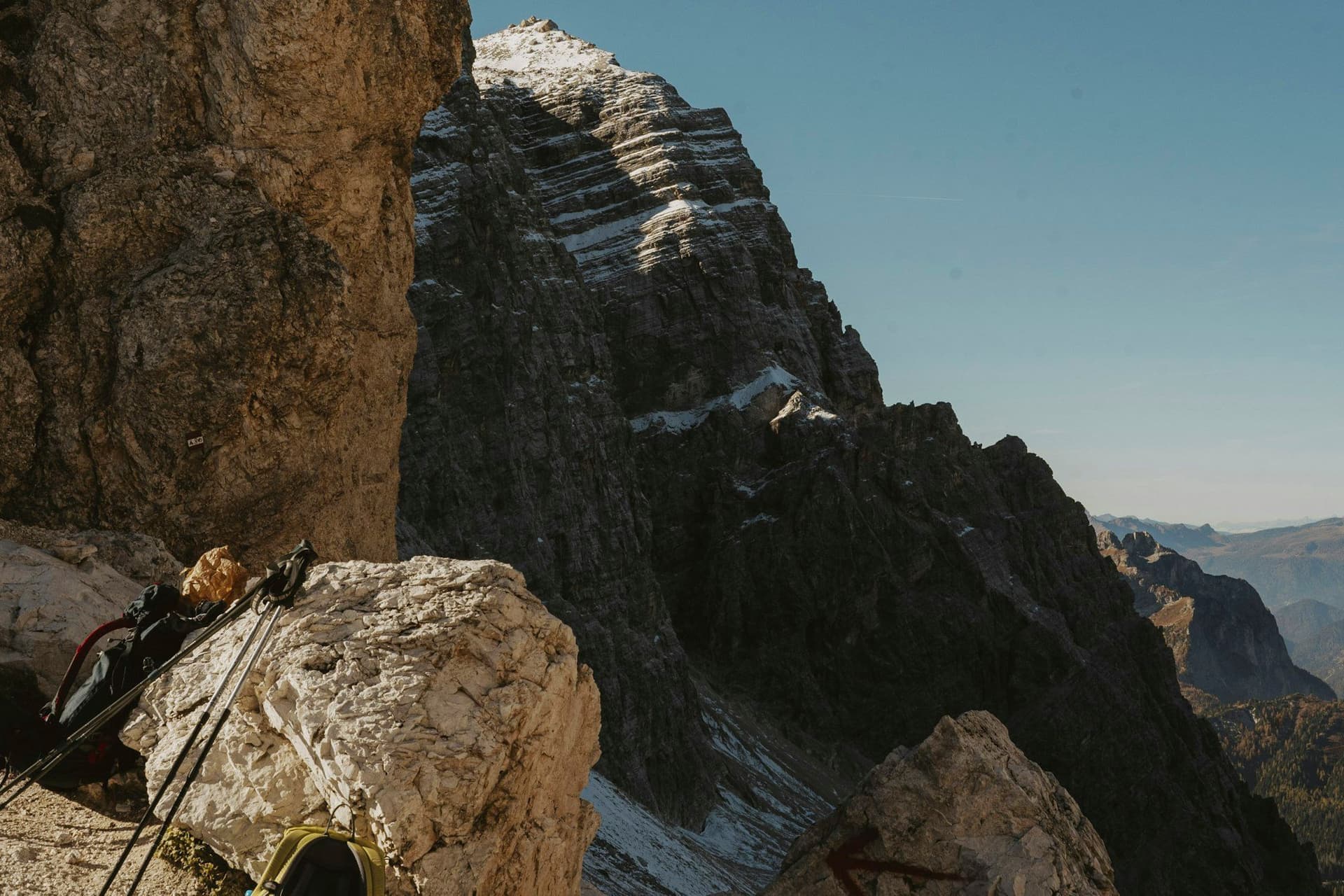 A pack and hiking kit set down on rock below a mountain