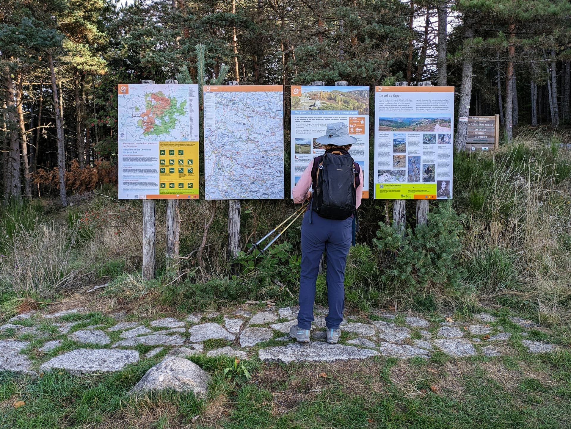 A walker reading route maps on a trailhead information board