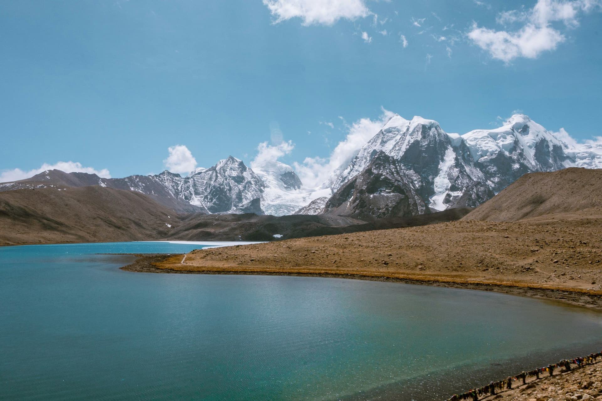 A turquoise glacial lake held below snow-capped peaks