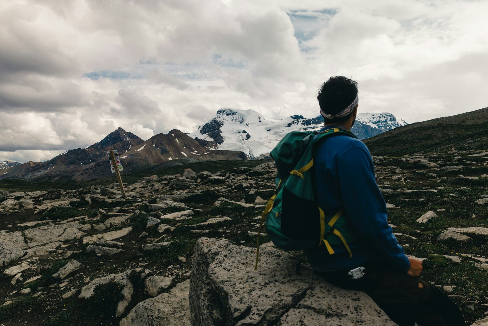 A trekker stopped on the trail, looking up at a glaciated peak